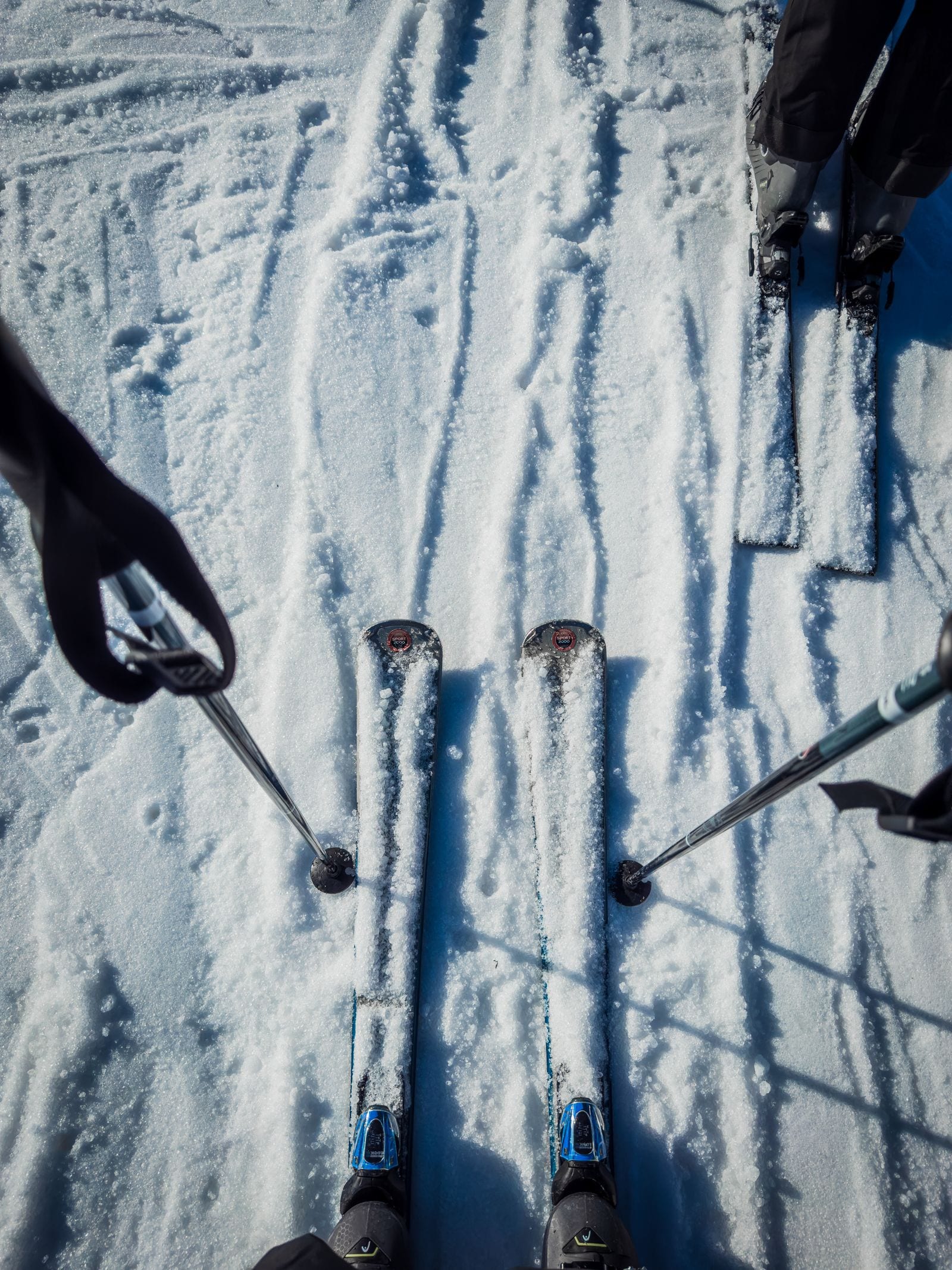 Nærbillede af ski og stave på en snedækket piste