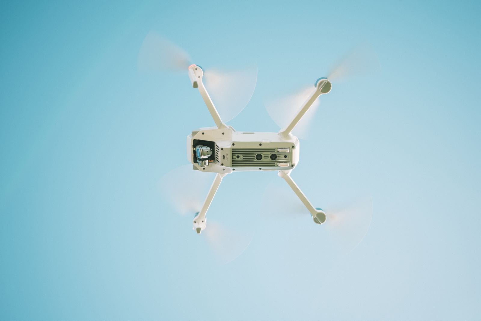 Hvid drone i luften under en klar blå himmel