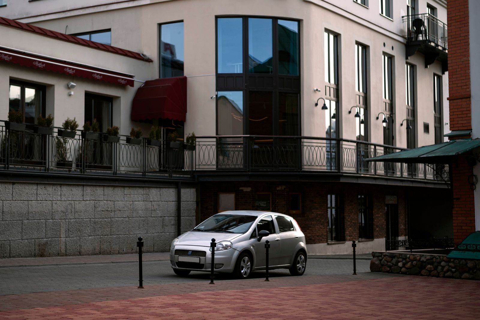 Sølvgrå kompaktbil parkeret ved en bygning i byen