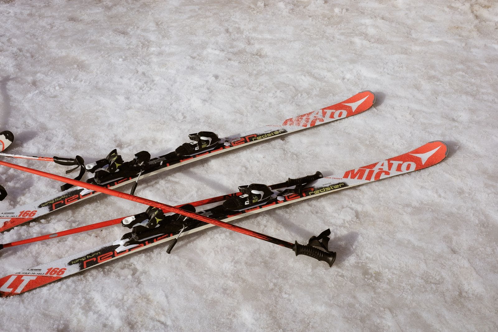 Røde og sorte ski med stave stukket ned i sneen